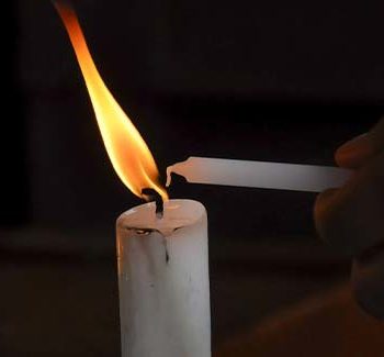 Candles being little by someone in a dark room